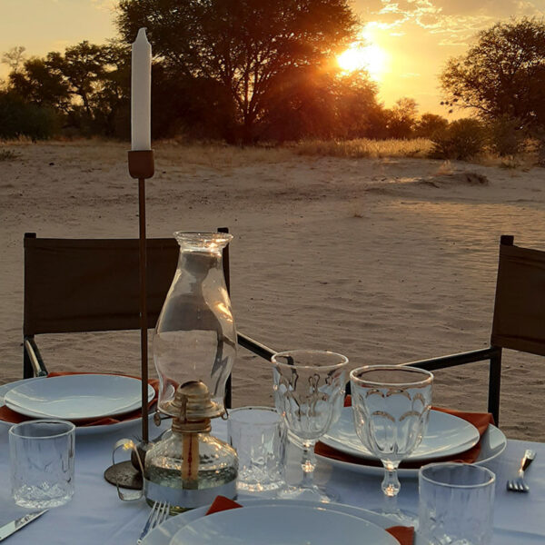 Gedeckter Tisch im Freien bei Sonnenuntergang auf der Lodge in Namibia.
