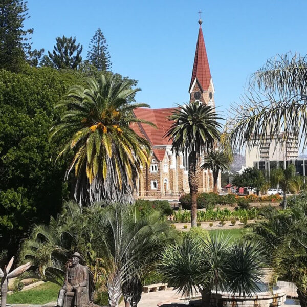 Die Christuskirche in Windhoek, umgeben von Palmen und Gartenanlagen, kulturelles Highlight der Safari-Tour „Best of Namibia“.